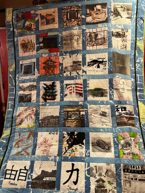 Close up of a quilt made form may different squares created by students focusing on the experiences of Japanese-American citizens detained in internment camps.